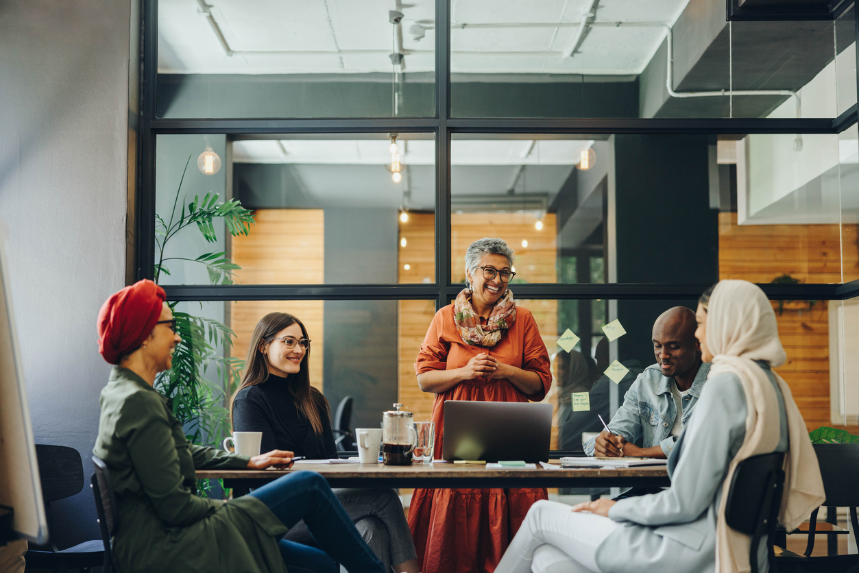 Successful businesspeople smiling happily during a meeting in a creative office. Group of cheerful business professionals working as a team in a multicultural workplace.