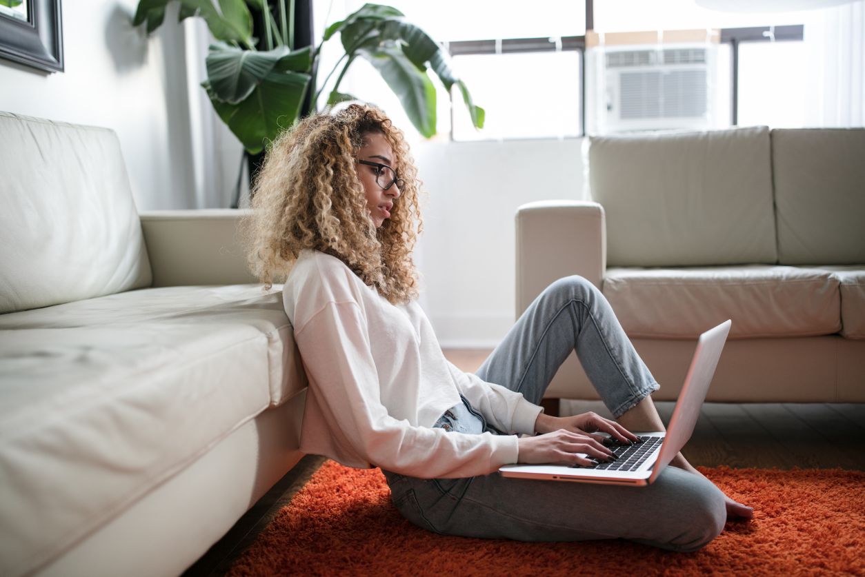 A woman sits on the floor while working on a laptop for an article about the skills communications leaders are hiring for right now. Photo by Thought Catalog on Unsplash