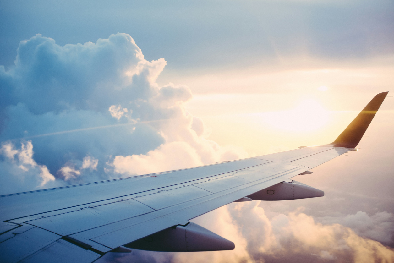 an image of a plane's wing in the sky intended to convey the notion of travel on an article about travel communications